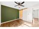 Bedroom featuring dark green accent wall, ceiling fan, and sliding barn door at 2500 Danforth Ln, Charlotte, NC 28208