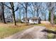 Inviting one-story home featuring a concrete driveway and picturesque front yard with mature trees at 2500 Danforth Ln, Charlotte, NC 28208