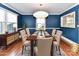 A staged dining room with blue walls, bright chandelier, hardwood floors, with crown molding and trim at 2919 Park Rd, Charlotte, NC 28209