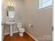 Bathroom features pedestal sink, wood floors, toilet and window at 3320 Tulip Tree Ln, Charlotte, NC 28273