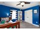 Bright blue bedroom featuring a ceiling fan, twin bed, and white bookshelf at 4000 Bridgewood Ln, Charlotte, NC 28226