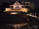 Exterior nighttime view of a large waterfront home with stone accents and a private dock at 5086 Windward Point Ln, Denver, NC 28037