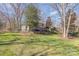 Expansive backyard with a covered seating area, a lush green lawn, and mature trees at 5213 Wood Lake Dr, Belmont, NC 28012