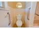 Neutral bathroom with tile, safety bars, toilet, and a round mirror above the toilet at 5830 W Nc 10 Hwy, Hickory, NC 28602