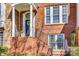 Close-up of a red brick porch with a wrought iron handrail and stairs leading up to a blue front door at 663 Sixth Baxter Xing, Fort Mill, SC 29708