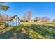 View of backyard shed, lawn, and home with mature trees on a sunny day at 723 W Zion Church Rd, Shelby, NC 28150