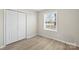 Bright bedroom with double door closet and window with tan color wood flooring throughout at 8009 Idlewild Rd, Indian Trail, NC 28079