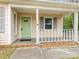 Inviting covered front porch with green door and gray shutters for a cozy entrance at 8101 Coxwood Ct, Charlotte, NC 28227