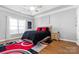 Bright bedroom featuring tray ceiling, wood floors, a large bed, and ample natural light for a restful retreat at 8328 Highland Glen Dr, Charlotte, NC 28269