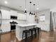 Modern kitchen with a large island, bar stool seating, stainless steel appliances, and hardwood floors at 925 Deep River Way, Waxhaw, NC 28173