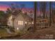 Back of house with wooden porch and stairs, surrounded by trees, bushes, and a well maintained backyard space at 109 Hawksnest Ln, Mooresville, NC 28117