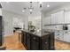 Modern kitchen featuring white cabinets, black appliances, an island with seating, and hardwood floors at 109 Hawksnest Ln, Mooresville, NC 28117