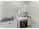 Well-lit laundry room with sink, cabinets, window, and modern appliances at 109 Hawksnest Ln, Mooresville, NC 28117