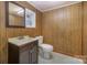 A quaint bathroom features a single sink vanity and toilet with wood paneled walls and tile floors at 127 Barry Oak Rd, Statesville, NC 28625