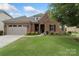 Charming brick home features a manicured lawn, attached garage, and inviting front entrance with manicured landscaping at 12726 Rusty Blackbird Way, Charlotte, NC 28278