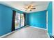 Blue bedroom with a ceiling fan, two windows with dark curtains, and light-colored flooring at 12727 Bullock Greenway Blvd, Charlotte, NC 28277