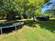 Lush backyard with mature trees, a trampoline, and covered boat storage at 2027 Downey St, Rock Hill, SC 29732