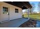 Inviting entrance featuring a glass-panel door, concrete patio, and pristine white vinyl siding, all complemented by a lush green lawn at 219 E Rice St, Landis, NC 28088