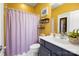 Bright bathroom featuring yellow walls, decorative shelving, and a shower-tub combo at 2205 Meleto Dr, Waxhaw, NC 28173