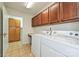 Convenient laundry room with a desk and wooden cabinets for storage and tile floors at 4709 Polo Gate Blvd, Charlotte, NC 28216