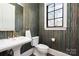 Stylish powder room with patterned wallpaper, a pedestal sink, and a black-framed window at 5608 Closeburn Rd, Charlotte, NC 28210