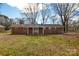 Backyard view of a brick home with a covered porch and large grassy yard at 571 Amity Se Ave, Concord, NC 28025