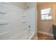 Bathroom features a shower-tub combo, white tile surround, and a window providing natural light at 571 Amity Se Ave, Concord, NC 28025