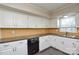 Bright kitchen with stainless steel sink, white cabinets, backsplash and black dishwasher at 571 Amity Se Ave, Concord, NC 28025