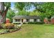 Charming single-story home featuring a well-manicured lawn, inviting walkway, and beautifully landscaped flowerbeds at 6126 Netherwood Dr, Charlotte, NC 28210