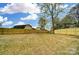 Large, fenced backyard with grass and a natural boulder feature and mature trees offers privacy and space at 9615 Riviera Dr, Sherrills Ford, NC 28673