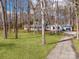 Scenic shot of a home nestled among mature trees with a driveway leading to an attached garage at 107 Rutledge Rd, Mount Holly, NC 28120