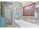 A stylish bathroom showcasing a soaking tub, a decorative window shade, tiled walls and floors, and a blue cabinet at 1135 Ben Black Rd, Midland, NC 28107