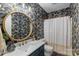 This bathroom features a decorative round mirror, a sink with storage, and wallpaper with nature motifs at 1135 Ben Black Rd, Midland, NC 28107