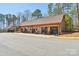 Large amenity building showcasing multiple glass doors, wooden siding, and rocking chairs at 1300 Dali Blvd, Mount Holly, NC 28120