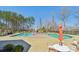 A community pool featuring lounge chairs and tables on a sunny day, surrounded by lush trees at 1300 Dali Blvd, Mount Holly, NC 28120