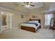 Bedroom featuring tray ceilings, carpet, and adjoining bath with a glass shower at 15100 Durmast Ct, Mint Hill, NC 28227