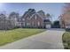 A well-maintained brick house with a long driveway leading to a garage, set on a spacious lawn at 15100 Durmast Ct, Mint Hill, NC 28227