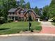 Beautiful two-story brick home with a manicured lawn, lush landscaping, and a long driveway at 15100 Durmast Ct, Mint Hill, NC 28227