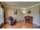 Cozy living room featuring hardwood floors, ample lighting, and a comfortable recliner chair near a piano at 15100 Durmast Ct, Mint Hill, NC 28227