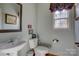 Cozy powder room features a pedestal sink, framed mirror, and a window providing natural light at 15100 Durmast Ct, Mint Hill, NC 28227