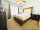 Well-lit bedroom features neutral carpet, a wooden bed frame, and a large window providing ample light at 1743 Park Grove Nw Pl, Concord, NC 28027