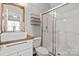 This bathroom features a walk-in shower with glass doors, a wood framed mirror, and a modern vanity, with a clean design at 18948 Kanawha Dr, Cornelius, NC 28031