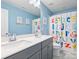 A bright bathroom with double sinks, colorful alphabet shower curtain, and playful decor at 2025 Sweet Magnolia Ln, Clover, SC 29710