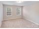 This bedroom features neutral walls, plush carpeting, and natural light from its two bright, airy windows at 220 Kenway Loop, Mooresville, NC 28117