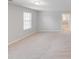 This bedroom features neutral walls, plush carpeting, and natural light from a bright window at 220 Kenway Loop, Mooresville, NC 28117