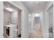 Bright hallway leads to laundry area with modern washer and dryer and storage shelves, freshly painted at 220 Kenway Loop, Mooresville, NC 28117