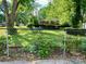 View of the the backyard, featuring green grass and mature trees; a small table and chairs is visible at 3701 Seaman Dr, Charlotte, NC 28217