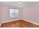 A well-lit bedroom featuring a window, hardwood flooring, and neutral walls at 5830 Kelden Walker Ln, Charlotte, NC 28269