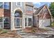 Close-up of a brick home with arched entryway, covered porch, and well-maintained landscaping at 717 Meadow Lake Dr, Matthews, NC 28105