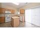 Bright kitchen with an island, white appliances, wooden cabinetry, and access to the backyard at 10422 Stokeshill Ct, Pineville, NC 28134